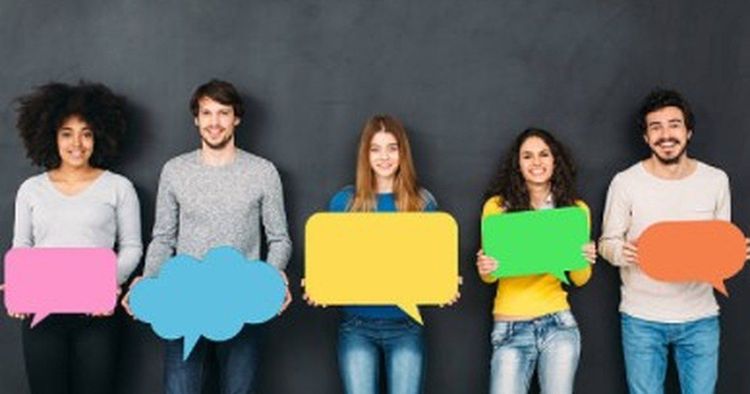 Five people holding colored speech bubbles in front of a dark wall